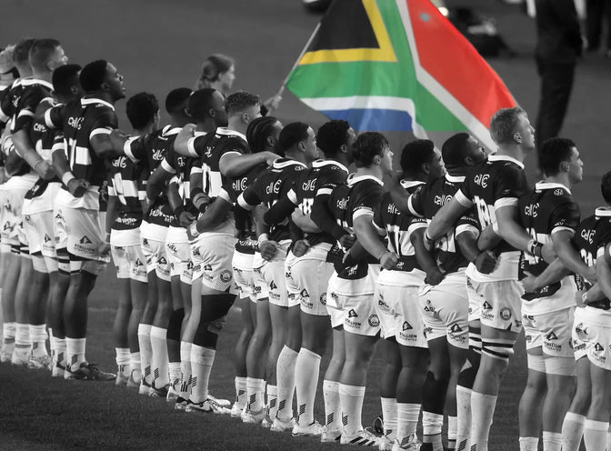 Both teams line up for the anthems before the tour match, a South African flag held above the Hollywoodbets Sharks side.