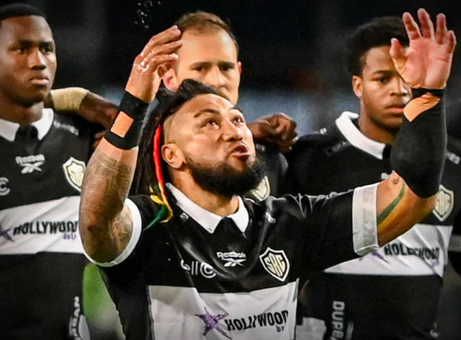 Ma'a Nonu performs a warrior challenge in reply to the Haka, surrounded by Hollywoodbets Sharks players.