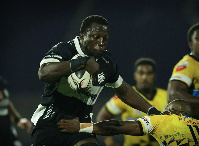 A Hollywoodbets Sharks XV player fends off a Sanlam Boland Kavaliers defender during a night match.