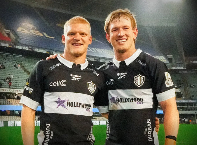 Two Hollywoodbets Sharks XV players stand arm in arm on the field after the final whistle.