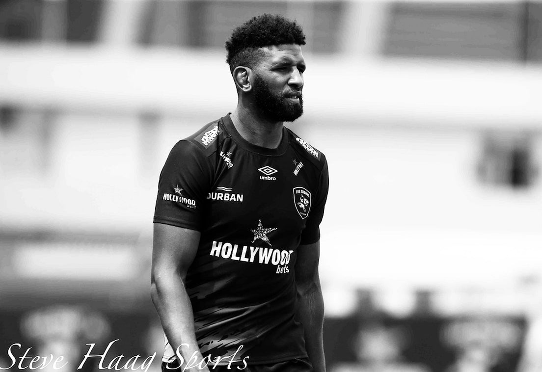 Black and white photo of Hyron Andrews in a Sharks training jersey, glancing to his left on a rugby field.