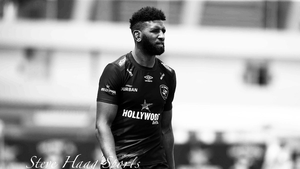 Black and white photo of Hyron Andrews in a Sharks training jersey, glancing to his left on a rugby field.