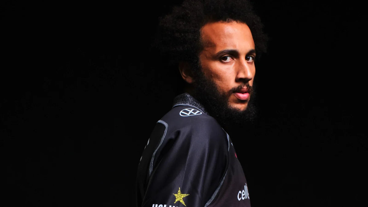 Studio portrait of a Hollywoodbets Sharks player in the club jersey, looking back over his shoulder against a black background.